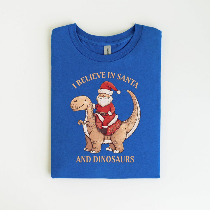 Unisex Baumwoll-T-Shirt "I Believe In Santa & Dinosaurs" | Lustiges Weihnachtsmann reitet auf Dino-Shirt-FaceeCo