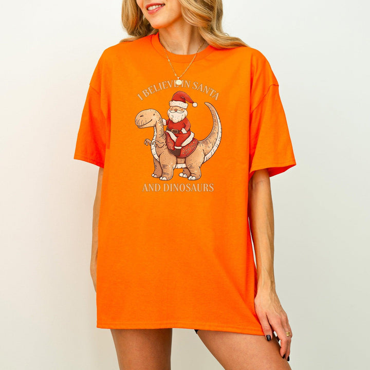 Unisex Baumwoll-T-Shirt "I Believe In Santa & Dinosaurs" | Lustiges Weihnachtsmann reitet auf Dino-Shirt-FaceeCo