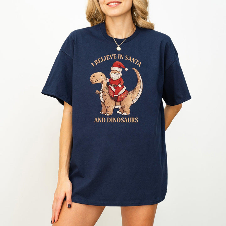 Unisex Baumwoll-T-Shirt "I Believe In Santa & Dinosaurs" | Lustiges Weihnachtsmann reitet auf Dino-Shirt-FaceeCo