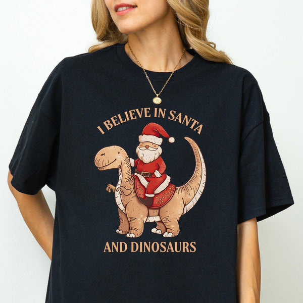 Unisex Baumwoll-T-Shirt "I Believe In Santa & Dinosaurs" | Lustiges Weihnachtsmann reitet auf Dino-Shirt-FaceeCo